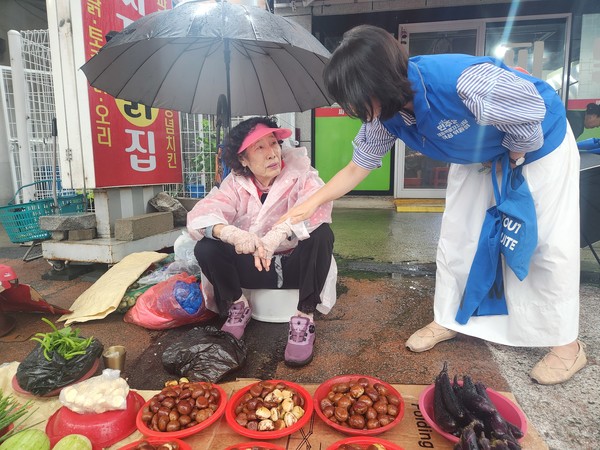 민주당세종시당 소속 한 위원이 17일 장날 노점상인이 파는 농산물을 구입하고 있다.(사진제공=세종시의회 김현옥의원실)