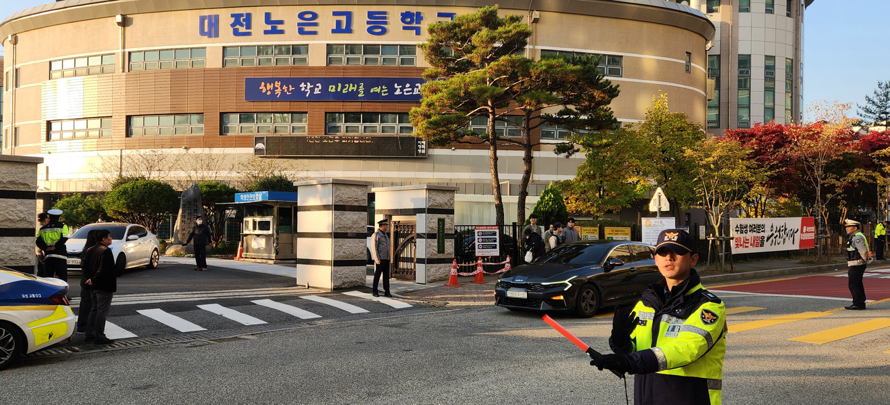 김선영 유성경찰서장(뒤쪽 교문 앞 가운데)을 비롯한 유성경찰서 소속 경찰관과 유성 모범운전자회가 수험생들의 안전한 입실을 위해 교통정리를 하고 있다. (사진=김현수 기자)