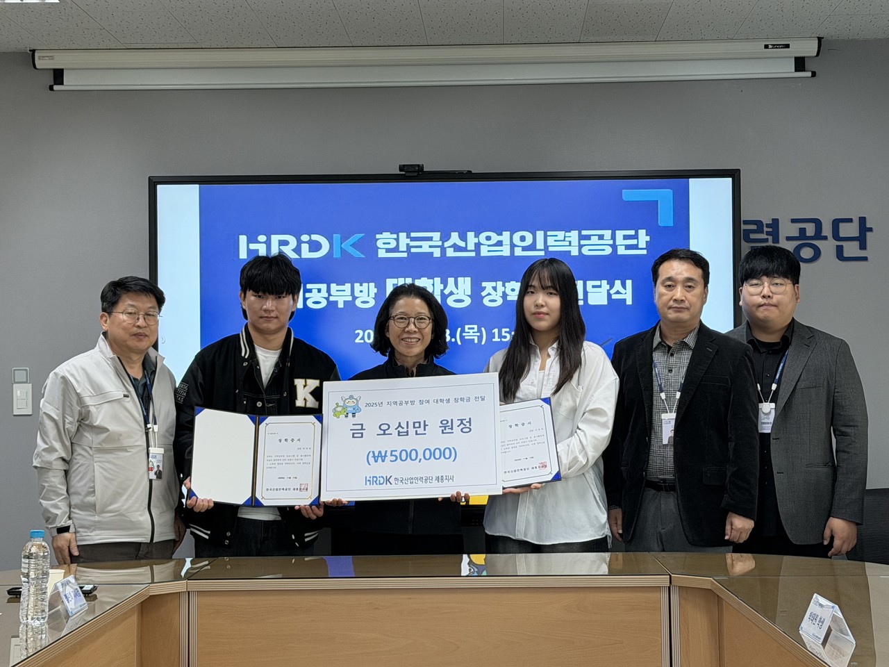 한국산업인력공단 정은희 세종지사장(가운데)은 13일 지역사회와의 상생·협력 및 발전을 위해 지역공부방 프로그램에 참여한 대학생 2명에게 장학금을 전달하고 기념사진을 촬영하고 있다. (사진제공=산업인력공단 세종지사)