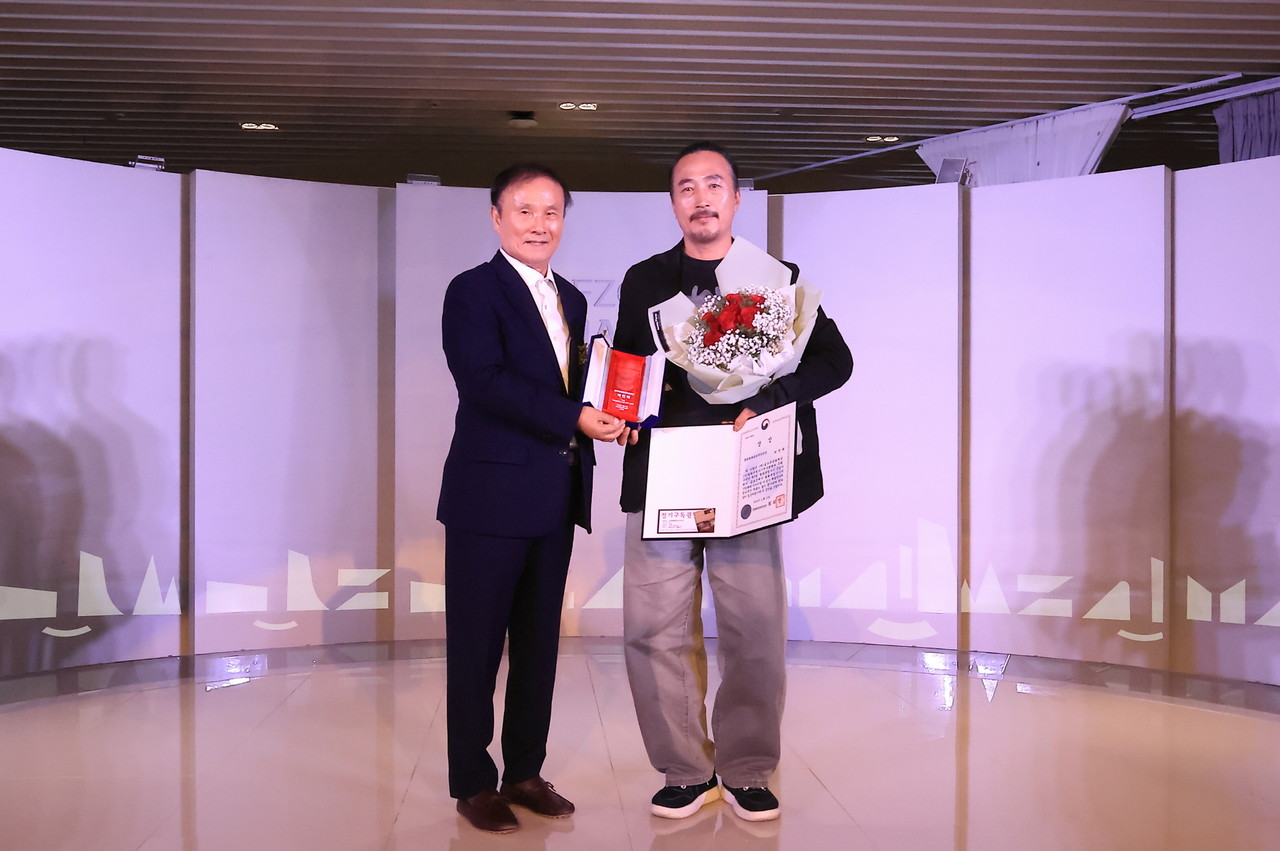 골프존문화재단 김영찬 이사장이 13일 공모전 시상식에서 문화체육관광부 장관상을 수상한 박연태 작가에게 시상을 하고 있다. (사진제공=골프존문화재단)