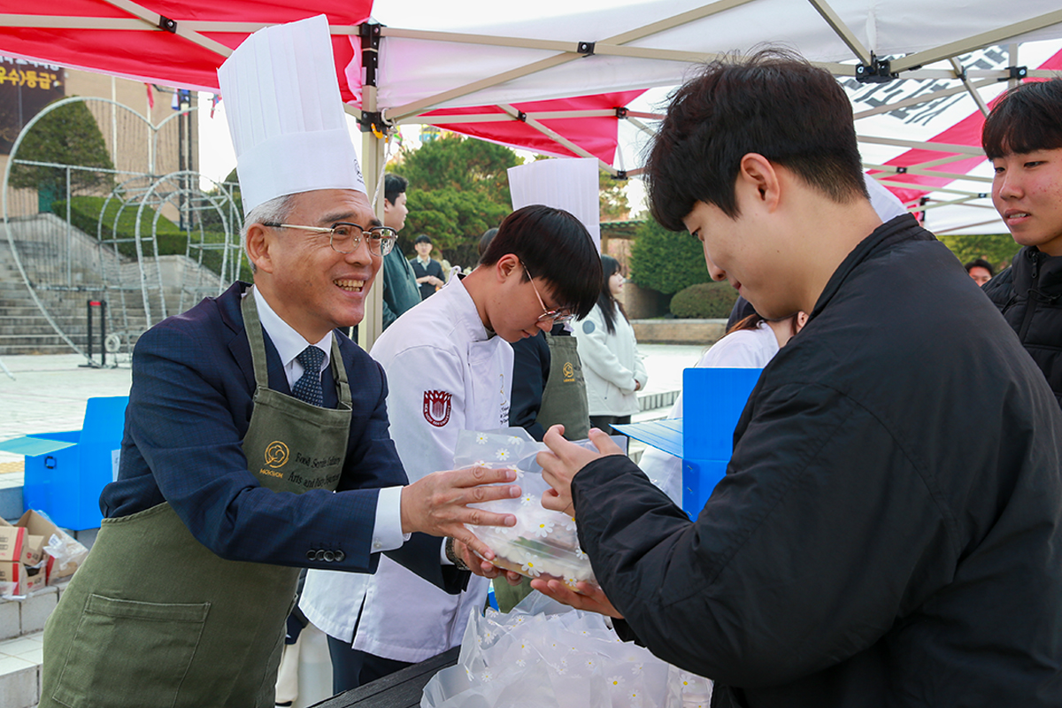 24일 이희학 총장(왼쪽)이 한 학생에게 간식 꾸러미를 전달하고 있다. (사진제공=목원대학교)
